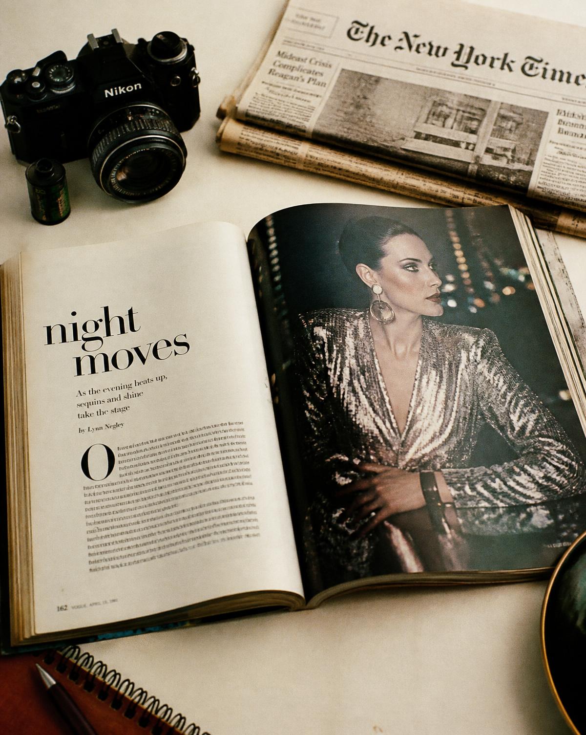 Vintage editorial still life with a camera, paper and open magazine spread.